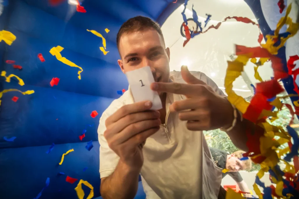 Účastník drží vyhraný lístok s číslom chytený vo Wind Boxe plnom konfiet